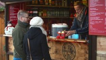 A couple purchase drinks from a market stall.