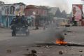 Policemen drive past burning debris during protests against President Joseph Kabila in Kinshasa on Tuesday.