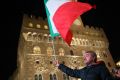 A 'Yes' campaign supporter waves the Italian national flag in Piazza della Signoria before Matteo Renzi speech.