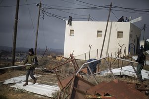 Jewish settler youth prepare barricades to block the entrance to a building in Amona, an unauthorized Israeli outpost in the West Bank, east of the Palestinian town of Ramallah, Thursday, Dec. 15, 2016.