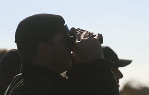 An official looks through his binoculars at an Afriqiyah Airways plane from Libya stands on the tarmac at Malta's Luqa International airport, Friday, Dec. 23, 2016.