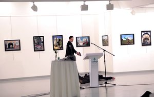 An unnamed gunman gestures after shooting the Russian Ambassador to Turkey, Andrei Karlov, at a photo gallery in Ankara, Turkey, Monday, Dec. 19, 2016.