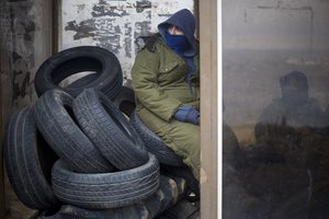 A Jewish settler youth sits on tires to be used as barricades to block the entrance to Amona, an unauthorized Israeli outpost in the West Bank, east of the Palestinian town of Ramallah, Dec. 15, 2016.