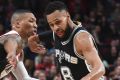 San Antonio Spurs guard Patty Mills drives to the basket  as Portland Trail Blazers guard Damian Lillard defends.