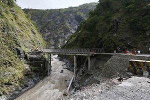 Workers assess the damage to Camp 5 bridge linking the summer capital of Baguio city in northern Philippines to Manila, a day after raging waters brought about by Super Typhoon Haima caused the foundation to collapse Friday Oct. 21, 2016