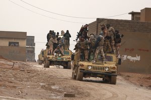 Iraqi army soldiers advance through rain towards Mosul, in the eastern Samah neighborhood, of Mosul, Iraq, Wednesday, Dec. 14, 2016.