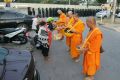 Monks at Thailand's largest Buddhist temple Wat Dhammakaya accept an offering while police line up in the background.