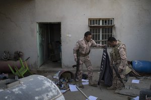 Kurdish Peshmerga soldiers look at a Islamic State flag inside an abandoned house in Faziliya, north of Mosul, Iraq, Wednesday, Nov. 2, 2016.