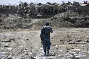 File - An Afghan Security policeman inspects the site of a suicide truck bombing, in Kabul, Afghanistan, Monday, Aug. 1, 2016.