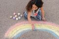 A young girl creating art on the concrete ground.