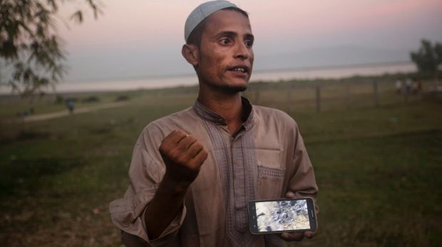Osman Gani, a Rohingya man from Myanmar, shows a video clip that he shot on his mobile phone while standing on the bank ...