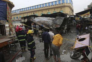 Iraqi people gather at the site of bomb attack in a busy market area in Baghdad's central al-Sinek neighborhood, Iraq, Saturday, Dec 31, 2016.