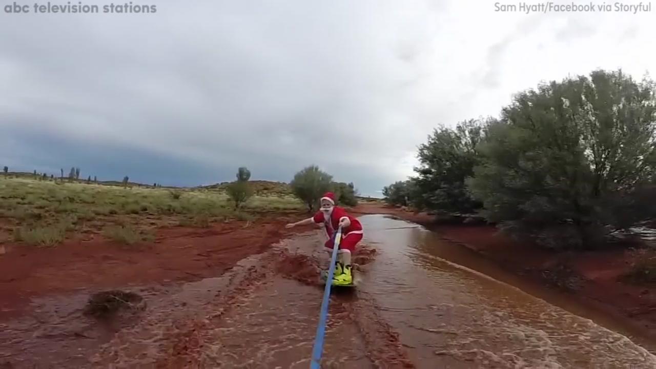 Image of man dressed as Santa wakeboarding. 