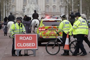 File - Police officers put a "Road Closed" sign and a traffic cone back in place, after members of the British military marched past on The Mall towards Buckingham Palace in London, Wednesday, Dec. 21, 2016.