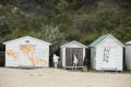 Pam Murphy and her granddaughters Holly and Emily inspect graffiti on their Point King beach box on Sunday
