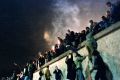 East German citizens climb the Berlin wall at the Brandenburg gate after the opening of the East German border was ...