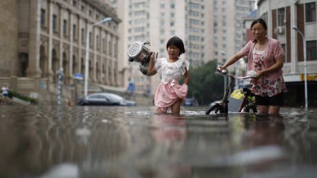 A child carries kettles through a flooded street with a woman in Tianjin, China, in July. 