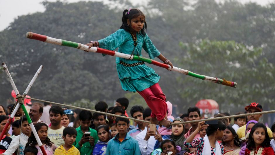 Indians watch Rani, 7, perform a rope balancing act at a public park on the first day of the New Year, in Kolkata.