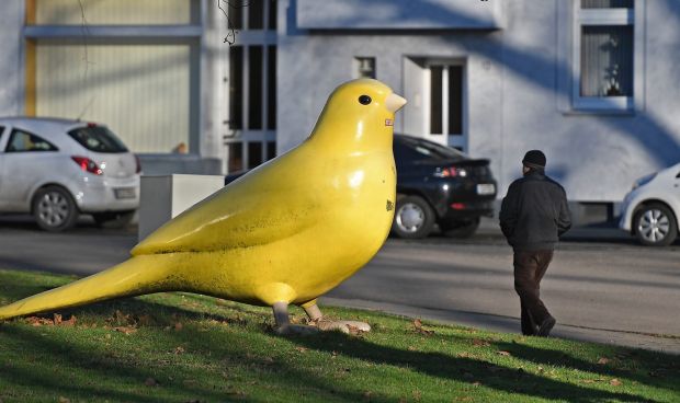 A big yellow bird sculpture shines in the afternoon sun in a street in Essen, Germany.