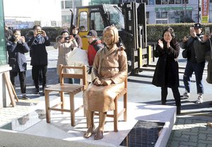 In this Dec. 30, 2016, photo, South Koreans take photos of a comfort-woman statue set up in front of the Japanese consulate in Busan, South Korea. Japan is recalling its ambassador to South Korea Friday, Jan. 6, 2017