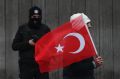 A man with a Turkish flag walks past a police officer during a memorial outside the Reina club. The killer remains at ...