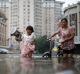 A child carries kettles through a flooded street with a woman in Tianjin, China, in July. 