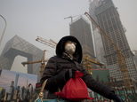 A woman wears a mask as she walks past a construction site as smog continues to choke Beijing on Friday, Jan. 6, 2017. The official Xinhua News Agency report...