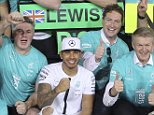 World champion Mercedes driver Lewis Hamilton of Britain, second placed, and his teammate winner Nico Rosberg of Germany celebrates with team members after the Emirates Formula One Grand Prix at the Yas Marina racetrack in Abu Dhabi, United Arab Emirates, Sunday, Nov. 29, 2015. Nico Rosberg completed a hat trick of victories to end the Formula One season when he won the Abu Dhabi Grand Prix on Sunday, profiting from a questionable tire strategy by his Mercedes teammate Lewis Hamilton.  Mercedes driver Nico Rosberg of Germany won the race. (AP Photo/Kamran Jebreili)