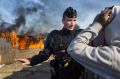 A police officer stands guard as migrant shelters burn down in the Jungle on Tuesday.