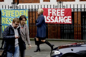 Swedish prosecutor Ingrid Isgren passes banners put up by supporters of Wikileaks founder Julian Assange as she walks to a vehicle on the second day at the Ecuadorian embassy in London, Tuesday, Nov. 15, 2016.