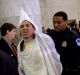 Code Pink activist Tighe Barry, dressed like a member of the KKK, centre, is removed by police officers after disrupting ...