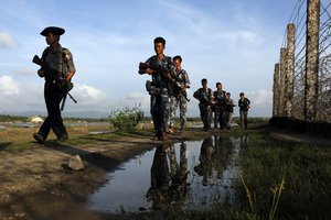 FILE - In this Friday, Oct. 14, 2016 file photo, Myanmar police officers patrol along the border fence between Myanmar and Bangladesh in Maungdaw, Rakhine State, Myanmar. Myanmar's government