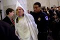 Code Pink activist Tighe Barry, dressed like a member of the KKK, centre, is removed by police officers after disrupting ...