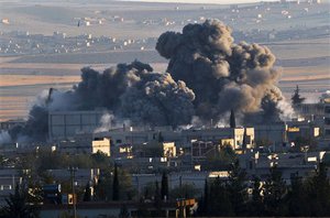 A bombs, seen top left, falls on an Islamic State position in eastern Kobani, during an airstrike by the US led coalition, seen from a hilltop outside Suruc, on the Turkey-Syria border.