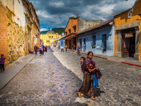 A woman and her child walk through the brightly coloured, but decaying stress of Antigua, Guatemala. This place is great ...
