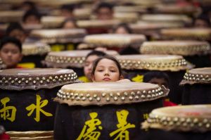 Young drummers stick out their heads among drums while preparing for the performance of "A Flourish of Hundreds Drums" ...