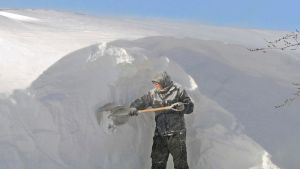 Cody Rohrich chips away at a large snowdrift while working in the blowing snow on a rooftop in downtown Bismarck on ...