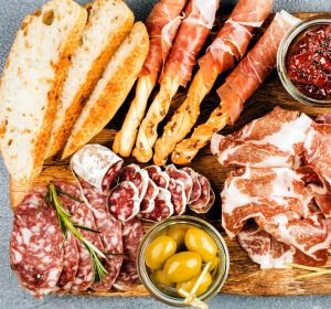 Meat appetizer selection or wine snack set. Variety of smoked meat, salami, prosciutto, bread sticks, baguette, olives ...