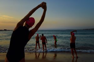 Members of the 'Wednesday 6am with Garry' swim club stretch at the waters edge before their routine swim at Bondi Beach, ...