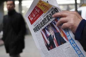 FILE - In this Thursday, Nov. 10, 2016, file photo, a man reads a newspaper with the headline of "U.S. President-elect Donald Trump delivers a mighty shock to America" at a news stand in Beijing.