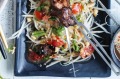 Green papaya salad used as a bed for grilled pork skewers.