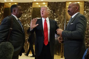 President-elect Donald Trump stands with comedian Steve Harvey, right, and businessman Greg Calhoun as he speaks with reporters in the lobby of Trump Tower in New York, Friday, Jan. 13, 2017.