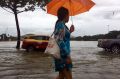 A woman walks by an overflowing lake on Koh Samui, Thailand earlier in January, 2017