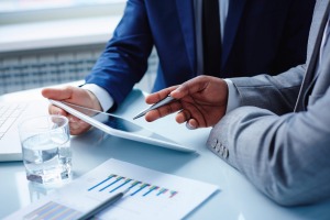 Image of businessmen hands during discussion of data in touchpad at meeting