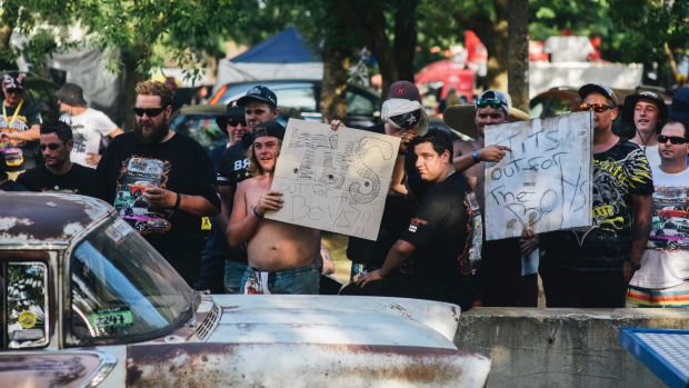 Men hold up signs along Tuff Street during Summernats.