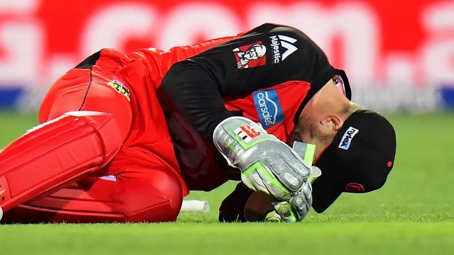 Peter Nevill of the Melbourne Renegades falls to the ground after being struck in the head by the bat of Brad Hodge of ...