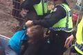 A protesters is hand-cuffed by police after the fences guarding the site were pushed down.