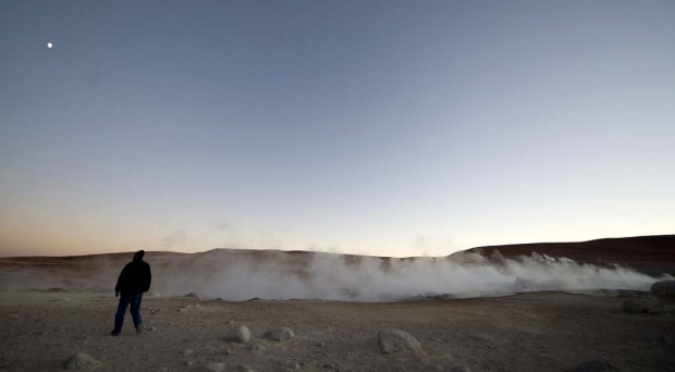 A tourist walks near the steam let off from fumaroles at the Uyuni salt flats, Bolivia.