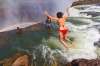 Woman jumps into Devil's Pool at Victoria Falls. It looks like she will be swept over the waterfall but a thick lip of ...