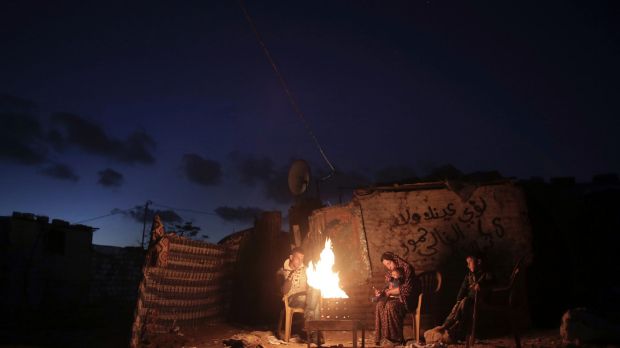 A Palestinian family warm themselves up with a fire outside their makeshift house during a power cut in a poor ...